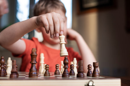 Young white child playing a game of chess on large chess board. Chess board on table in front of school boy thinking of next move, tournamentの写真素材
