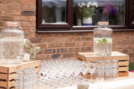 Glass jars of lemonade on party bar. Drinks on wedding party. Outside catering drinks service. Business, catering service. Drinks on summer party. Catering table with glasses, big glass jars of lemonade or cocktail for outdoor party. Cocktails party.の写真素材