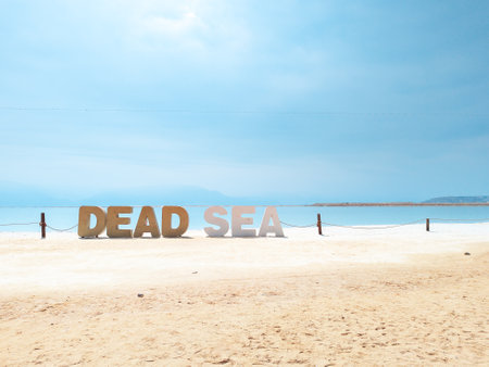 Landscape view on Dead Sea salt crystals formations, clear cyan green calm water with big letters saying Dead sea at Ein Bokek beach, Israelの写真素材