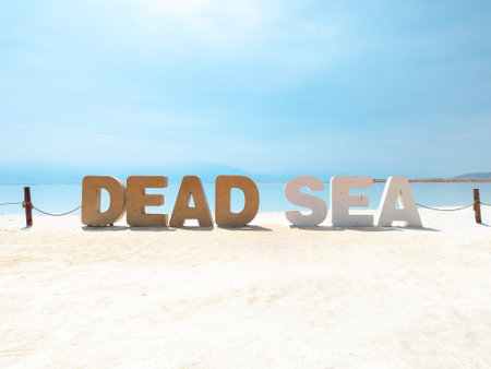 Landscape view on Dead Sea salt crystals formations, clear cyan green calm water with big letters saying Dead sea at Ein Bokek beach, Israelの写真素材