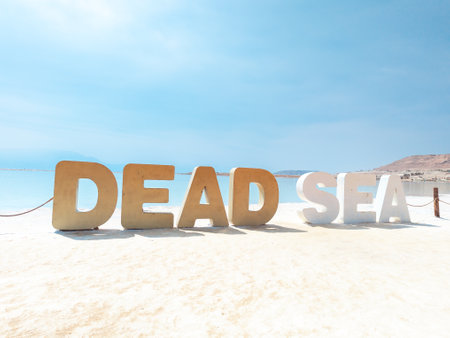 Landscape view on Dead Sea salt crystals formations, clear cyan green calm water with big letters saying Dead sea at Ein Bokek beach, Israelの写真素材