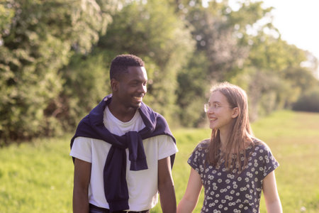 Young multiethnic couple walking together in the park on a sunny day