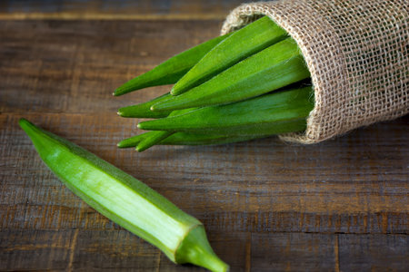 A heap of raw okra or Lady's fingers or gumbo  in a bagon wooden background