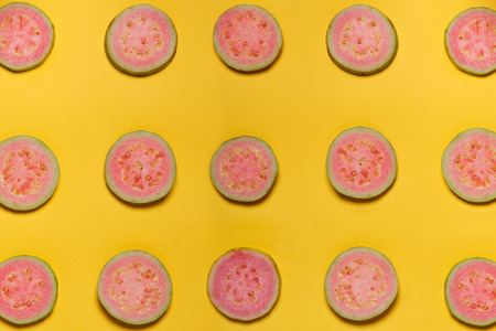 Top view of rounded pink guava on yellow background, patternの写真素材