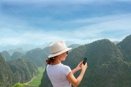Modern technology and communication. Be online in travel. hiking and trekking concept. Young woman using smartphoneの写真素材