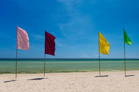 Four bright flags on the white sand  beach with copyspaceの写真素材