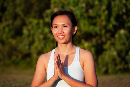 people, fitness, sport and healthy lifestyle concept - close up young smiling asian girl making yoga...