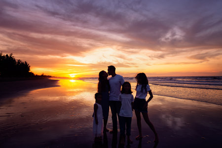 Silhouettes of happy family on beach during sunsetの写真素材