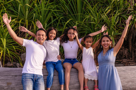family, leisure and people concept-young active parents with three daughters with arms up- enjoying...