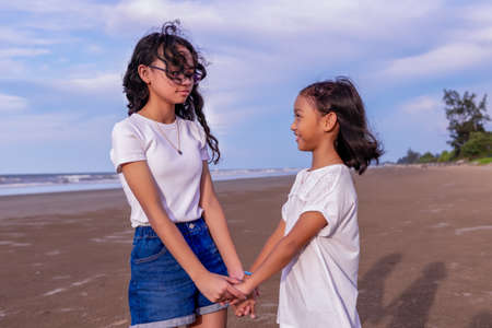 summer, childhood, leisure and people concept-two female asian siblings hold each other's handsの写真素材