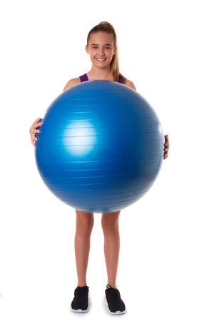 Slim and fit teen girl holding a swiss ball. Full length shot on white background, isolatedの写真素材