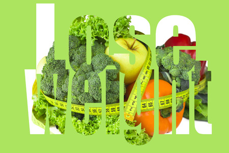 Ingredients of healthy nutrition surrounded by a centimeter tape. Fruits, vegetables and greens on a white table. Inscriptionの写真素材