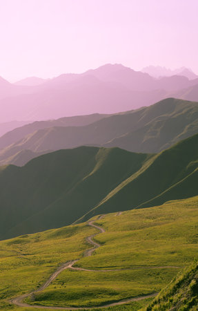 Country road leaving into the distance. Silhouettes of purple mountain ranges on the horizon on...