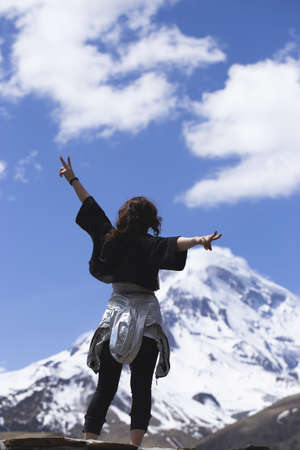 Woman traveler enjoys the view of the top of Mount Kazbek in Georgia. Hiking in the mountains, active lifestyle for girlsの写真素材