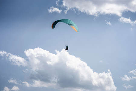 Paragliding with a pair of instructors. Bright blue sky with beautiful white fluffy clouds. Leisure with active adventures. Tourism in Georgiaの写真素材