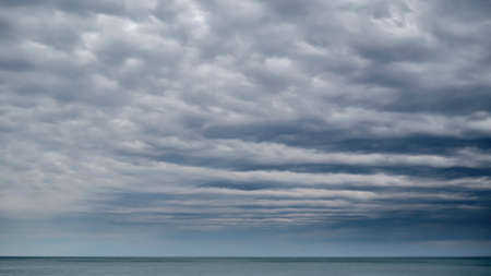 The space of the sky is closed to the horizon by rows of clouds. Moody weather on the seaside.の写真素材