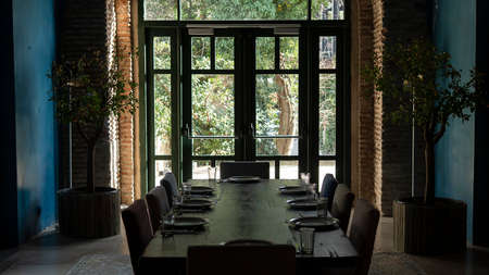 Luxurious living room interior in an old castle. Window with a door to the garden. Served wooden table. Ancient brick wallsの写真素材