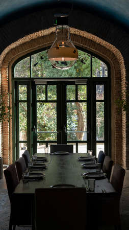 Luxurious living room interior in an old castle. Window with a door to the garden. Served wooden table. Ancient brick wallsの写真素材