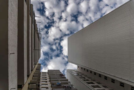Blue sky with fluffy white clouds in the gap between the towers of high-rise buildings. Dry linen on balconies.の写真素材