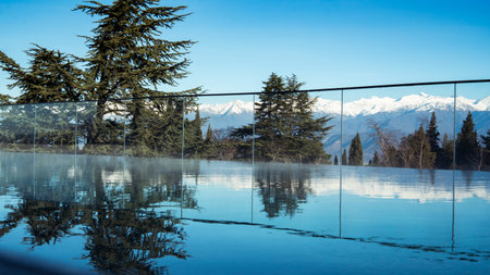 Outdoor swimming pool at the resort. Mountain landscape panorama. Snow on the tops of the mountain...