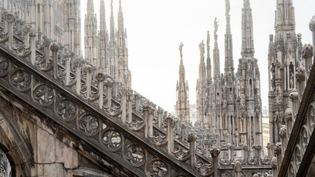 The image shows the intricate Gothic architecture of Milan's iconic Duomo Cathedral. Tall spires,...
