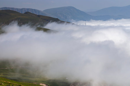 A breathtaking mountain landscape with rolling green hills, scattered cottages, and winding trails....