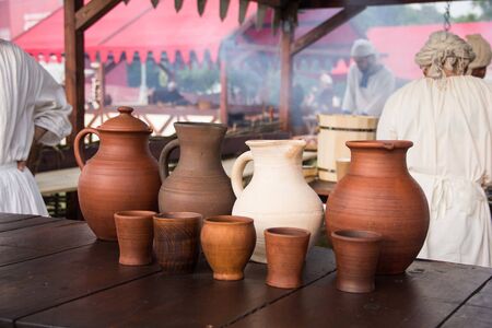 A wine jug and set of clay cups on the wooden tableの写真素材
