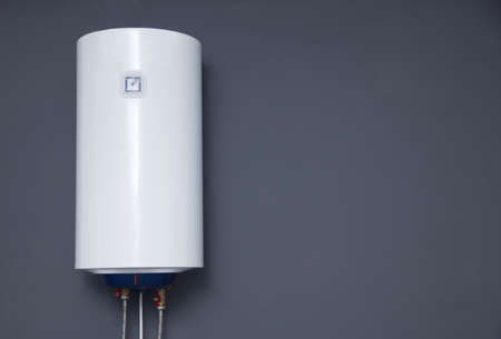 Modern electric boiler on a gray plain wall.の写真素材