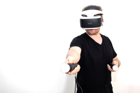 A young man is playing VR. The joysticks. White background. Image of a happy bearded young man in a...