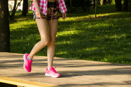 Womens feet in pink sneakers in the park. A walk in the city park