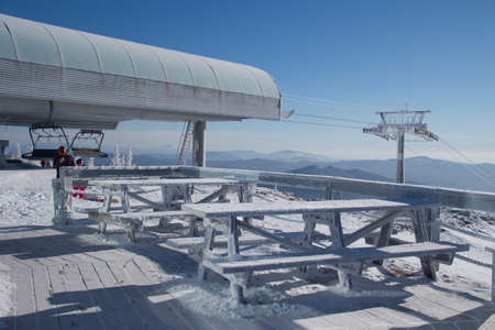 Tables on the top of a snow-covered mountain. The background of the winter space of the ski lift and the summitの写真素材