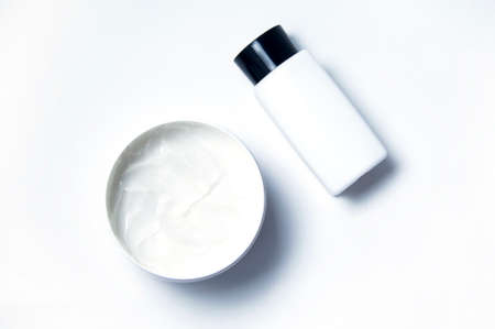 White cosmetic cream on a white background and a white bubble with a black lid. Empty packaging transparent jar for cosmetic cream, isolated on a white background.の写真素材