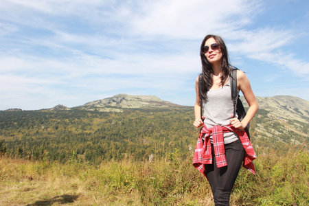 The girl travels through the mountains. Stylish hipster female traveler with a backpack.の写真素材