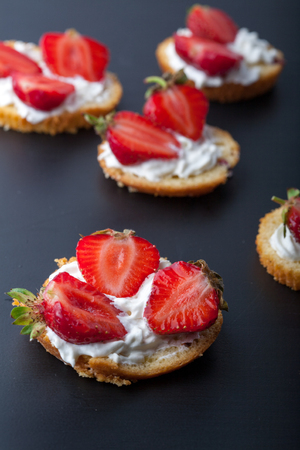 Fluffy buttermilk biscuits shortcake with red ripe strawberries and fresh whipped cream on a black backgroundの写真素材