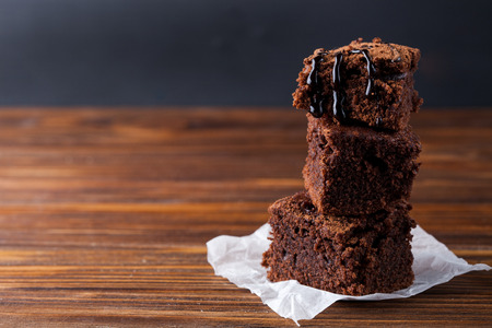 Stack of homemade brownies on dark moody background. Chocolate cake closeup. Copy space.の写真素材
