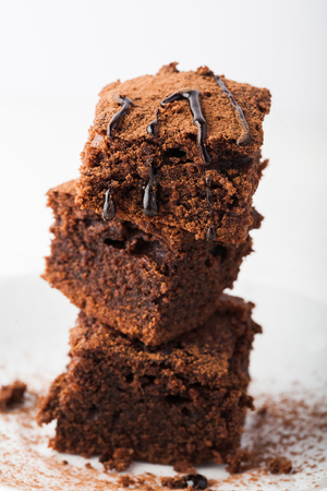 Stack of brownies on white wooden background. Chocolate cake close up. Copy space.の写真素材