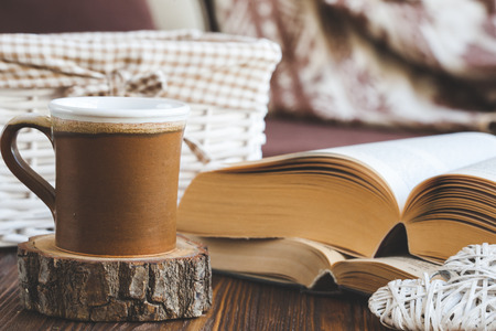 Details of still life in the home interior living room. Beautiful tea Cup, cut wood, books and pillows, candle on wooden background. Vintage, rustic. Cosy autumn-winter conceptの写真素材
