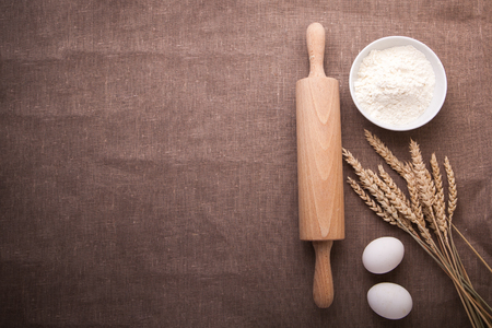Baking ingredients. Flour, eggs, wheat and rolling pin on  table cloth. Rustic. Copy spaceの写真素材