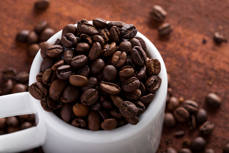Photo closeup of coffee beans in white cup. Rusty background. Copy space.の写真素材