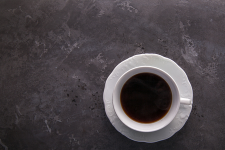 White cup of coffee on dark grey beton background decorated with coffee beans. Copy spaceの写真素材
