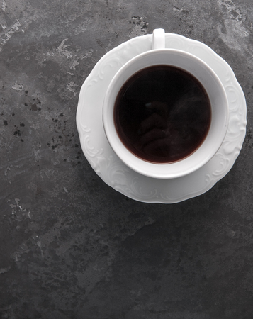 White cup of coffee on dark grey beton background decorated with coffee beans. Copy spaceの写真素材