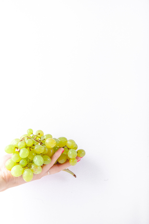 Hand holding green grapes on white background minimalism. Copy spaceの写真素材