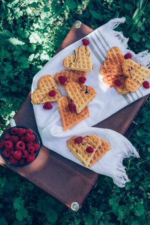 Sweet heart shaped waffles with raspberries for dessert outdoor picnic in the garden.の写真素材