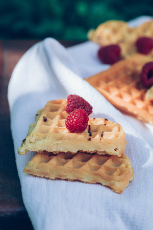Sweet heart shaped waffles with raspberries for dessert outdoor picnic in the garden.の写真素材