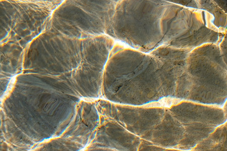 Transparent sea water surface with ripples and sunlight reflections. Abstract background