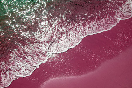 Aerial view of pink sand beach with white foam and waves.の写真素材