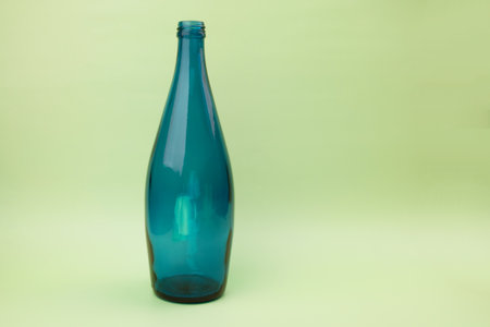 Empty blue glass bottle on green background with copy space for text.の写真素材