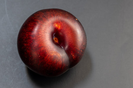 Ripe red plum on a dark background. Close-up.