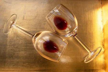 Two wine glasses with red wine on a golden background. Toned.の写真素材