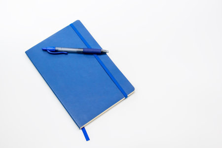 Blue notebook and pen on white background. Top view. Copy space.の写真素材